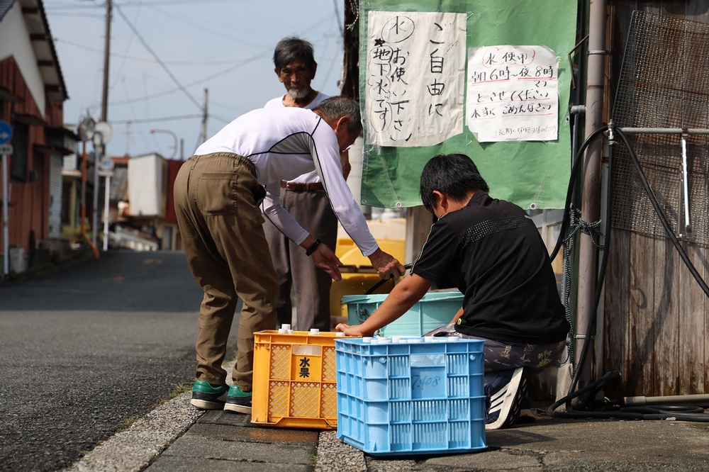 People collect water from a tap in the aftermath of the earthquake (AFP/Getty)
