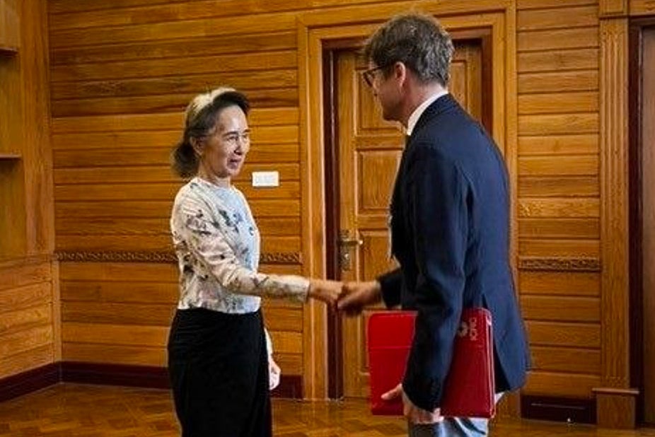 Myanmar's ousted leader Aung San Suu Kyi, left, shakes hands with Arnaud de Baecque, resident representative of the International Committee of the Red Cross (AP)