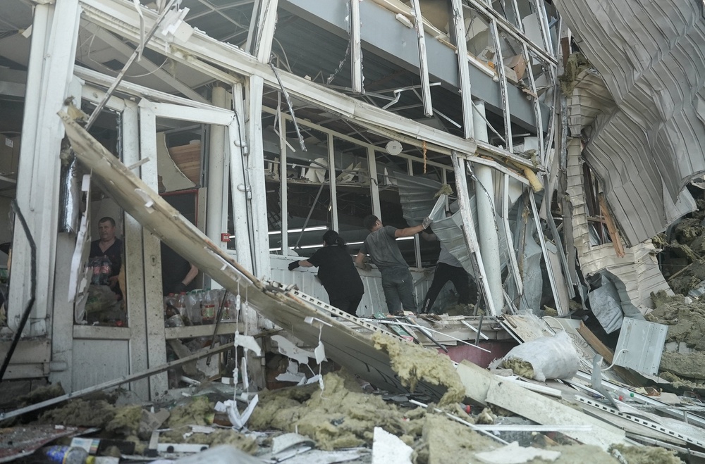People clean debris in a shopping mall hit by a Russian air strike in Sumy on Thursday (Reuters)