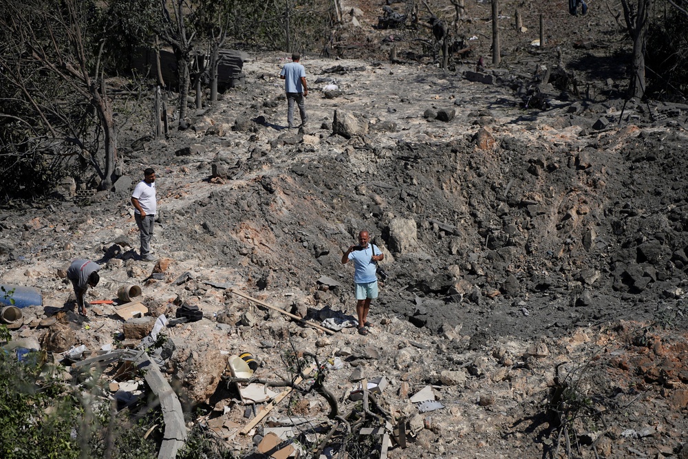 People and journalists stand at a site hit by Israeli strikes that occurred in the early hours of Thursday, according to Lebanon’s state news agency NNA, in Burj al-Shamali (Reuters)