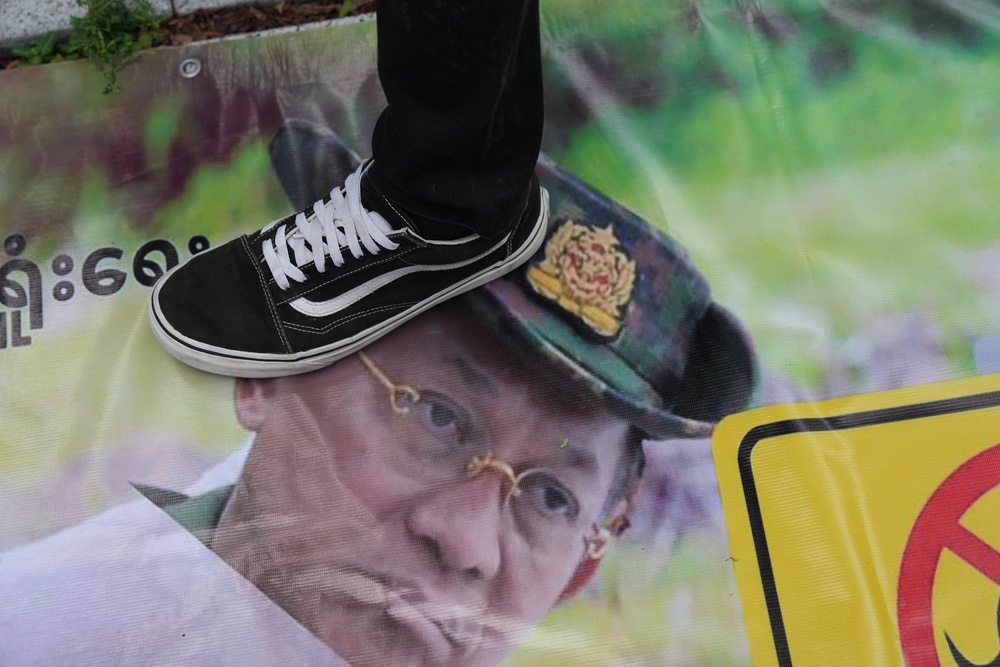 A Myanmarese national living in Thailand steps on a poster of Min Aung Hlaing during a protest in Bangkok (AP)