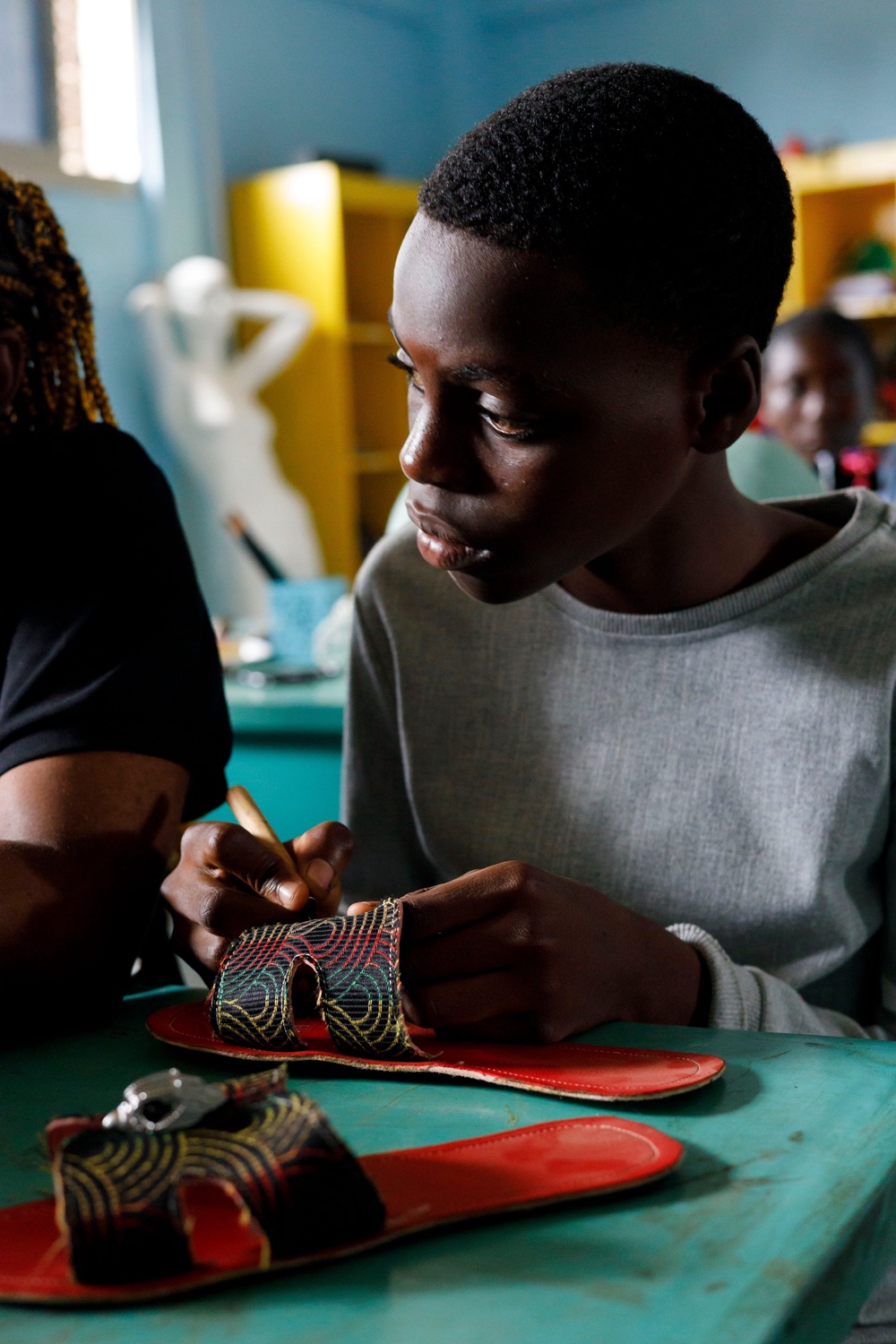 A student at The Creative Corner learns the art of shoemaking, carefully stitching each piece by hand as part of a programme that teaches every stage of the making process. (Copyright: The Creative Corner)