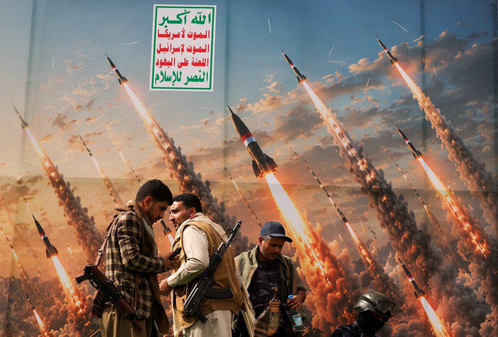Houthi activists stand on a platform against a banner depicting Houthi missiles, at an anti-Saudi rally amid an escalation with the kingdom (Reuters)