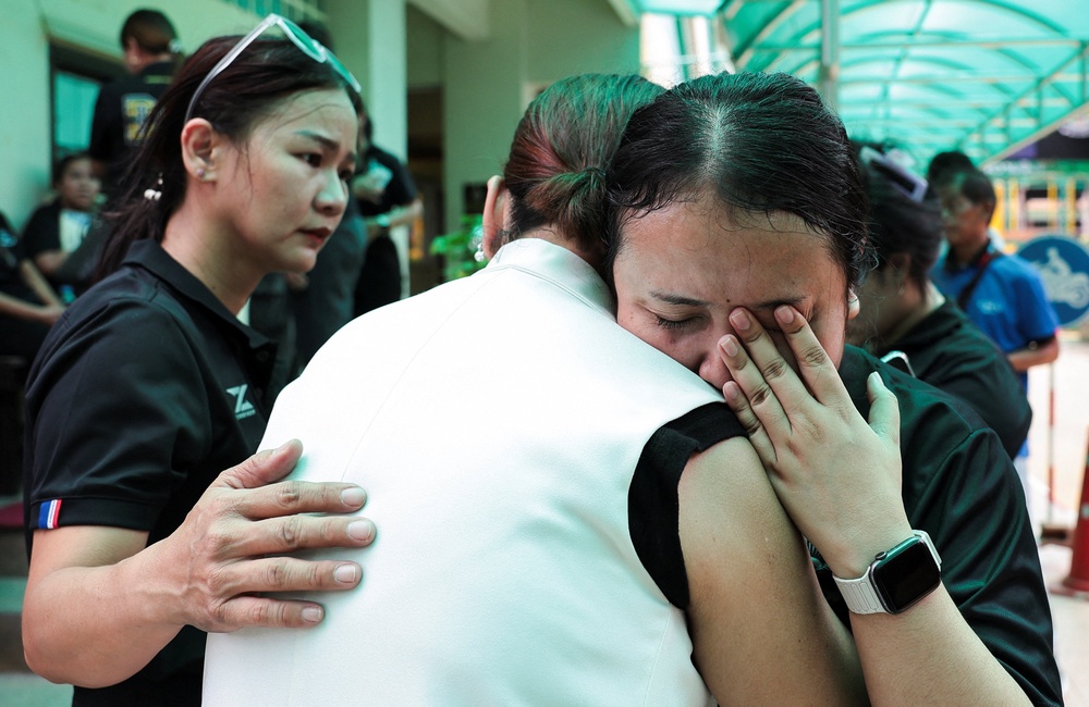 A teacher reacts while embracing a person at Debsirin Nonthaburi School (Reuters)