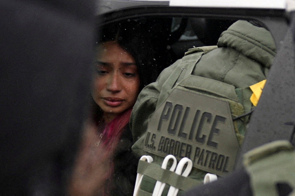 A detained woman sits inside a vehicle surrounded by federal agents, as immigration enforcement continues after a U.S. Immigration and Customs Enforcement (ICE) agent fatally shot Renee Nicole Good on January 7 (Reuters)