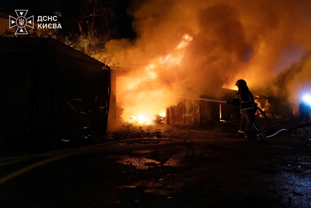 Firefighters work at a compound of car garages damaged during overnight Russian missile strikes in Kyiv (Reuters)