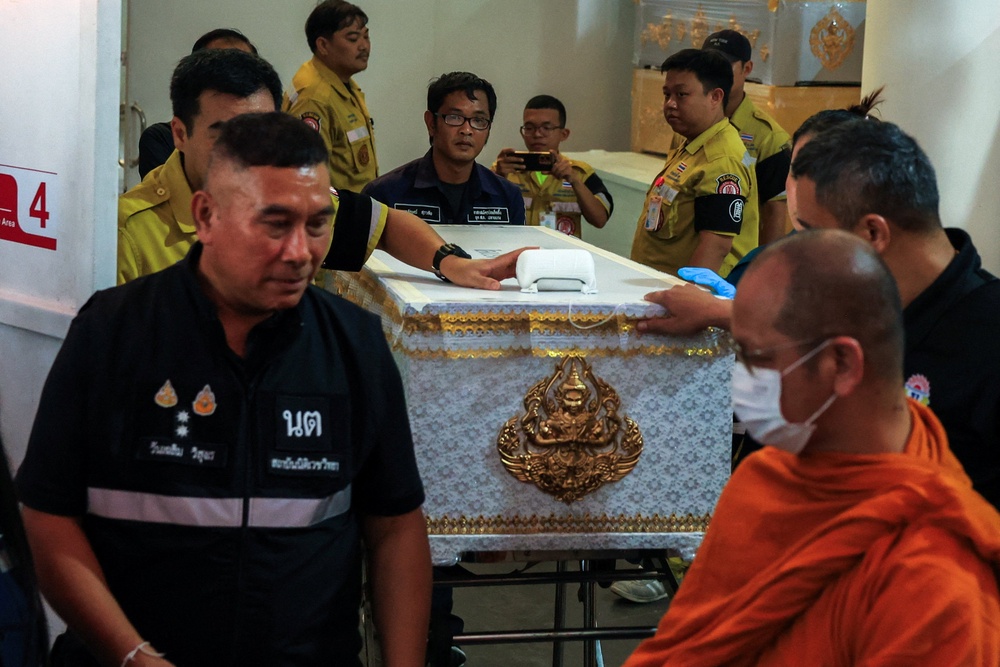 A Buddhist monk leads as workers move a coffin with the body of a victim killed in a deadly shooting at Debsirin Nonthaburi School (Reuters)