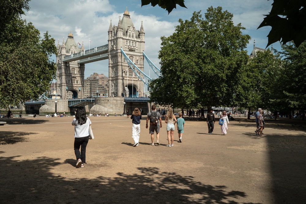Tourists walk on the parched earth and sun-damaged grass near Tower Bridge on Sunday (Getty)