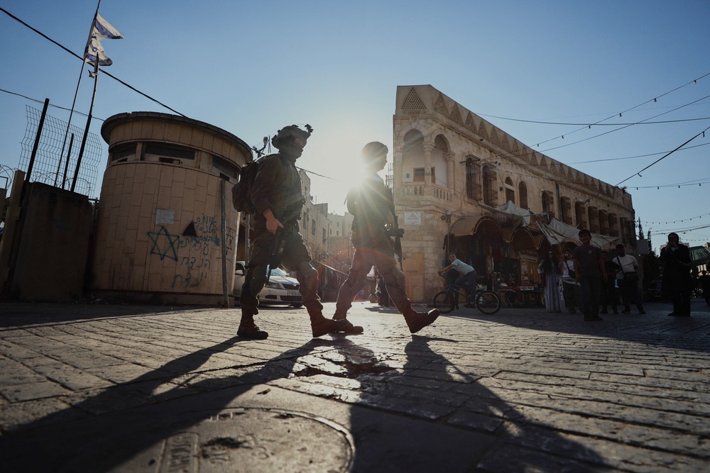 Armed Israeli soldiers patrol a street in the Old City of Hebron, in the occupied West Bank, on 8 August 2026 (AFP/Getty)