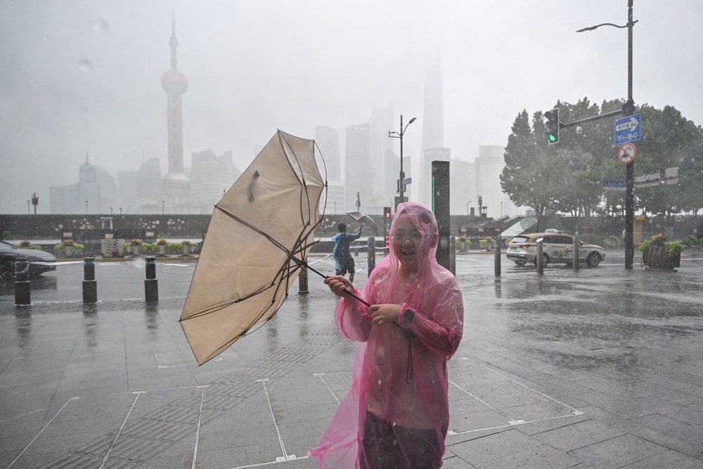 People use umbrellas to shelter from the rain as they walk on the Bund a day after Typhoon Dolphin (AFP/Getty)