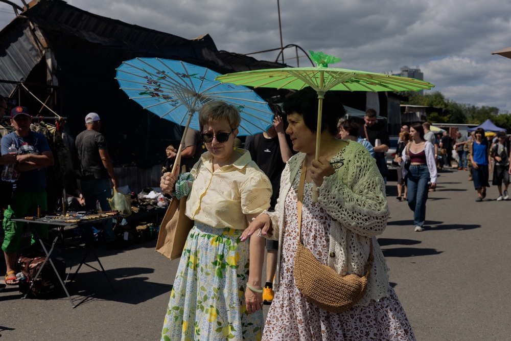 Women holding umbrellas to protect themselves from the sun walk along a damaged street market (AFP/Getty)