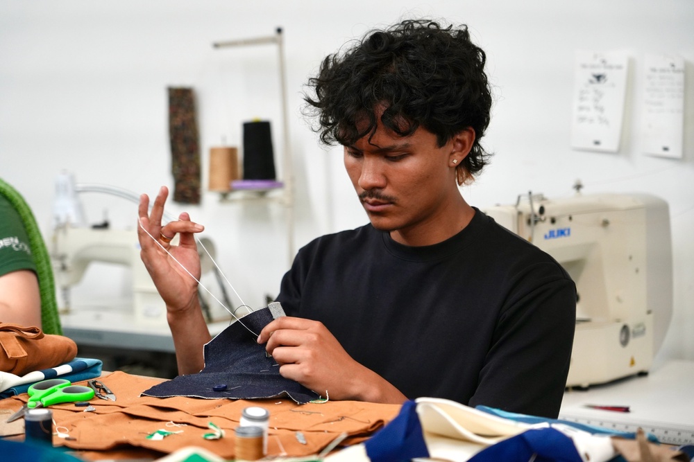 Jesse Sanchez practices sewing during a clothing repair workshop at a Levi's retail store in downtown San Francisco in July 2026 (AP Photo/Terry Chea)