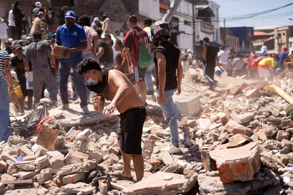 Residents dig through the debris of a collapsed building after an earthquake in Cali on Monday (Reuters)
