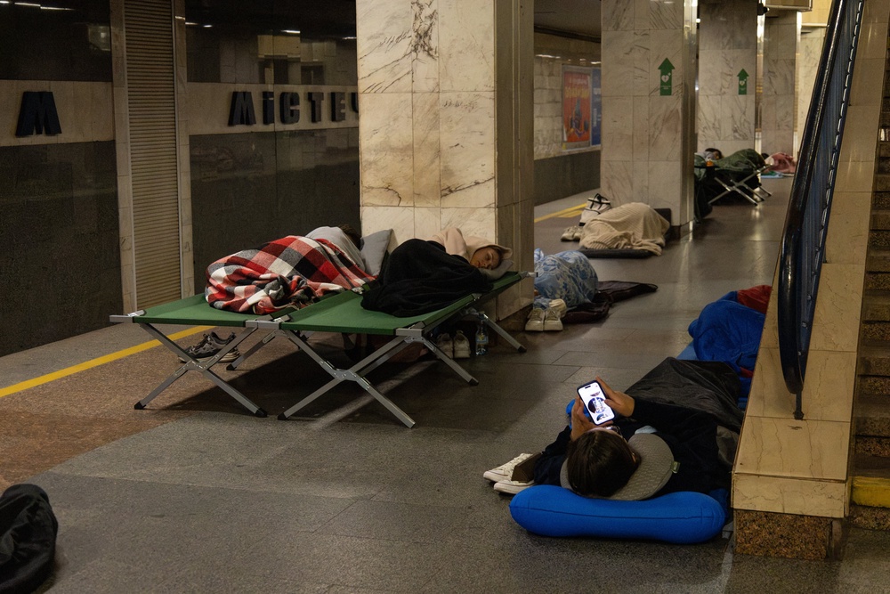 A person checks a smartphone and others sleep as they take shelter overnight in a Kyiv metro station, following warnings of a possible Russian air attac (AFP/Getty)