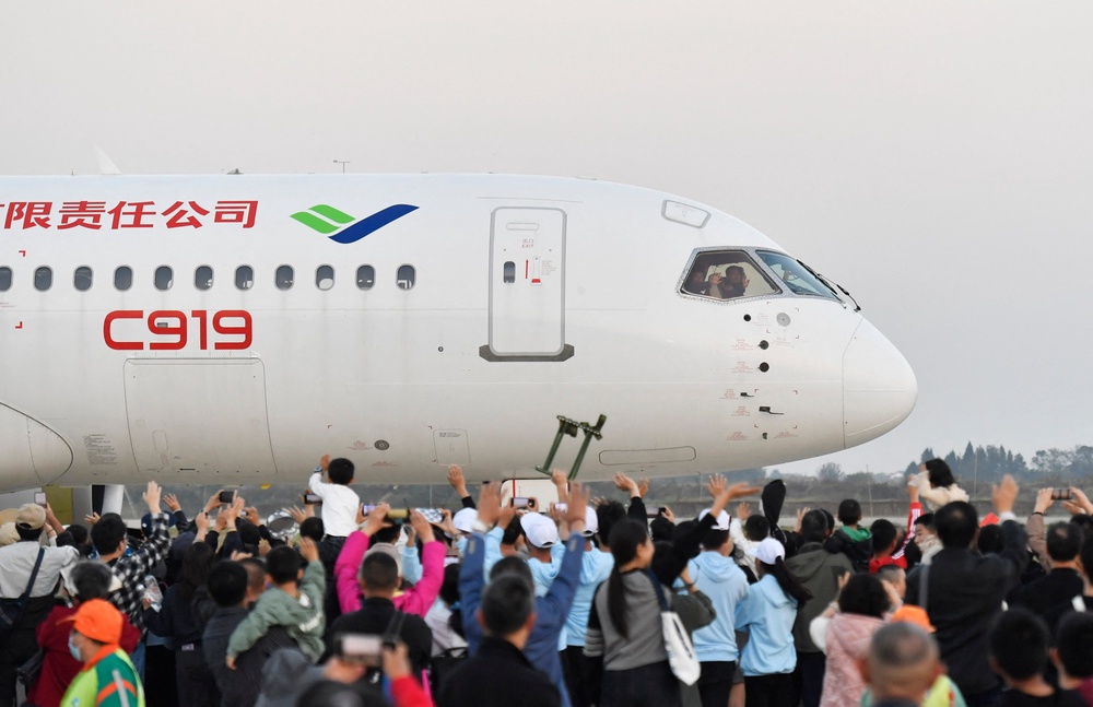 A crowd waves to pilots of China's domestically produced C919 passenger jet at an air show in Nanchang, Jiangxi, on 2 November 2024 (AFP/Getty)