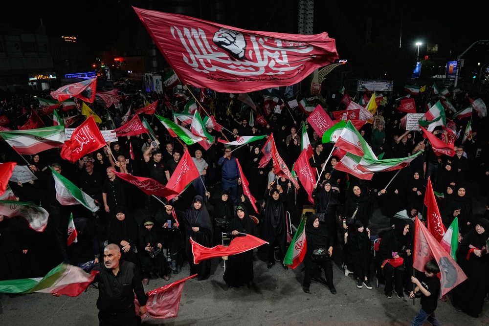 Iranian pro-government demonstrators wave flags in a gathering at a square in Tehran, Iran, (AP)