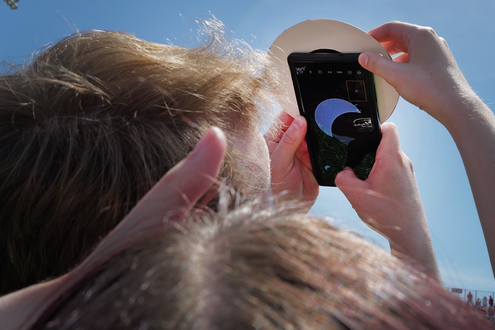 A couple uses a cell phone to photograph the solar eclipse. (Getty)
