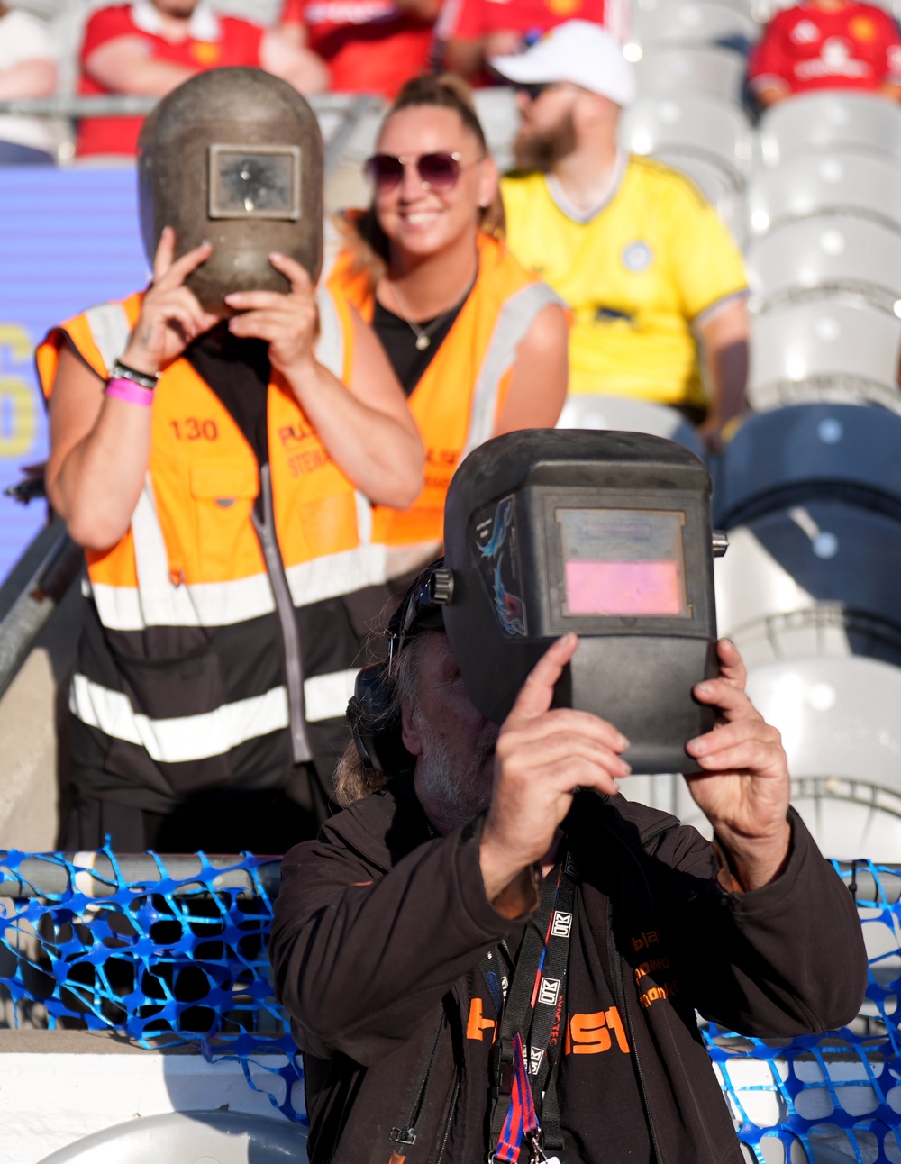 Stewards wearing welding helmets to watch the solar eclipse (Niall Carson/PA) (PA Wire)