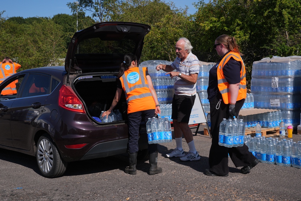 Thames Water personnel handing out bottled water to residents at Roding Sports Centre in Chigwell, Essex, following a water main burst on Chigwell Road in South Woodford (PA)