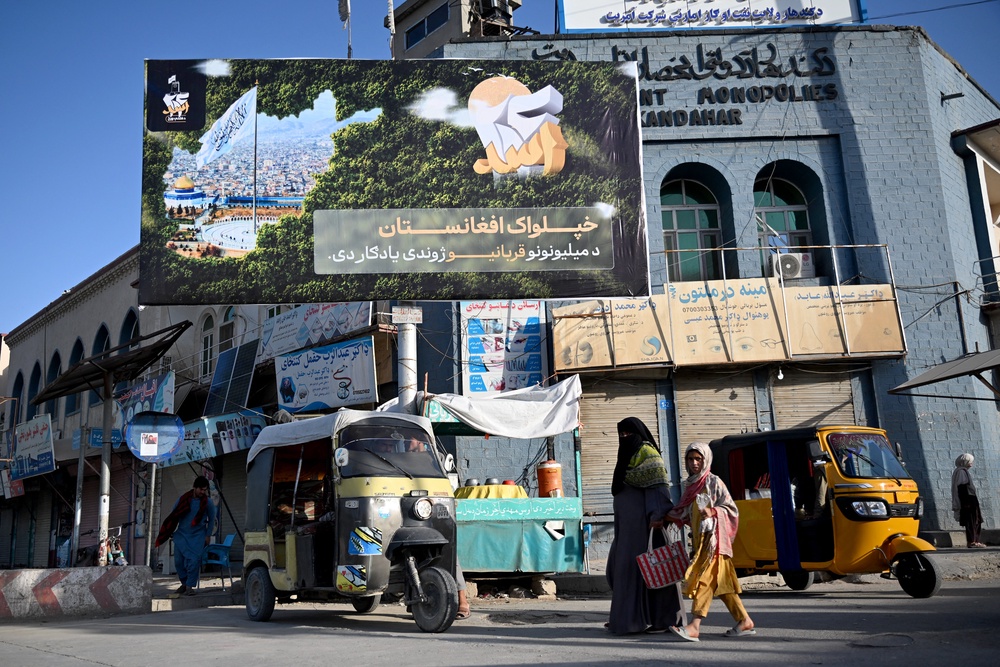 Afghans walk past a board displaying slogans by the Taliban administration in Kandahar (AFP/Getty)