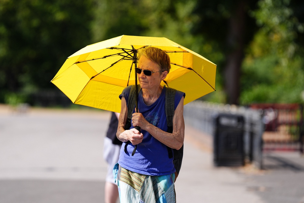 A person uses an umbrella to shield themselves from the sun at Cannon Hill Park in Birmingham (Jacob King/PA) (PA Wire)