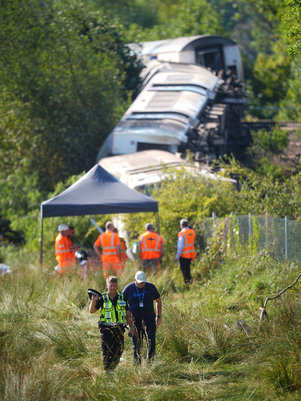 Officers inspecting the train derailment on Friday (PA)