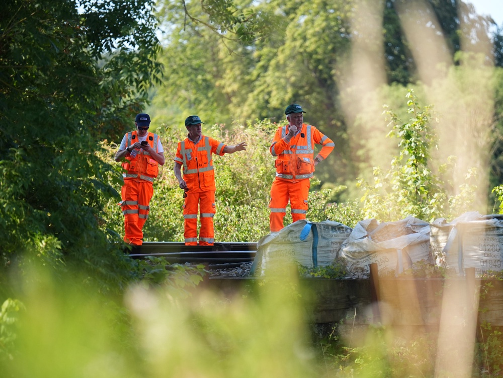 Members of the Rail Accident Investigations Bureau (RAIB) on the tracks at the scene (PA)