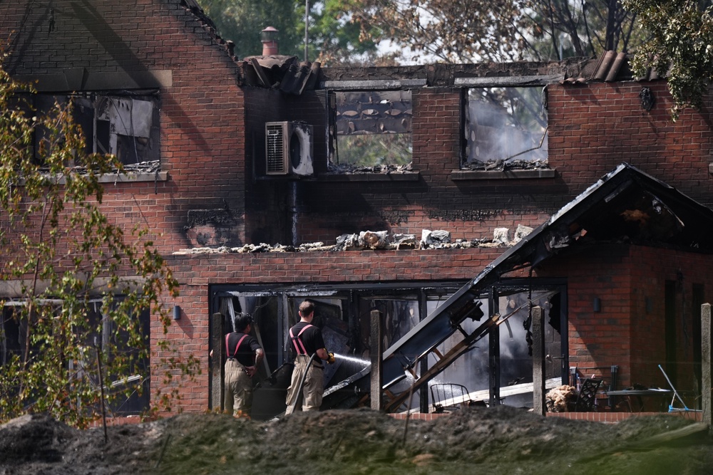 Firefighters looking at the burnt out remains of a house following a huge blaze in Stourbridge, in the West Midlands (PA)
