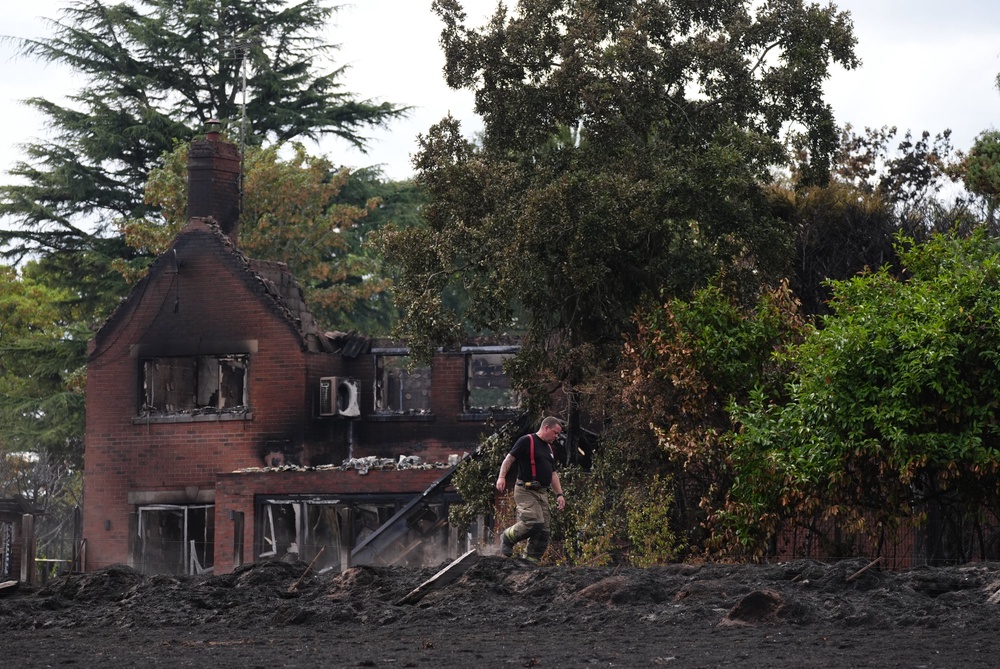 A firefighter checks the ground around the burnt out remains of a house following a huge blaze in Stourbridge, in the West Midlands, which forced some people to flee after it started tearing through homes (PA)
