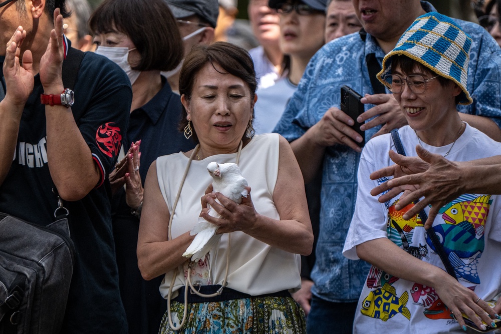 A woman prepares to release a white dove as a tribute to the war dead at the Yasukuni Shrine in Tokyo on 15 August 2026 (AFP via Getty)