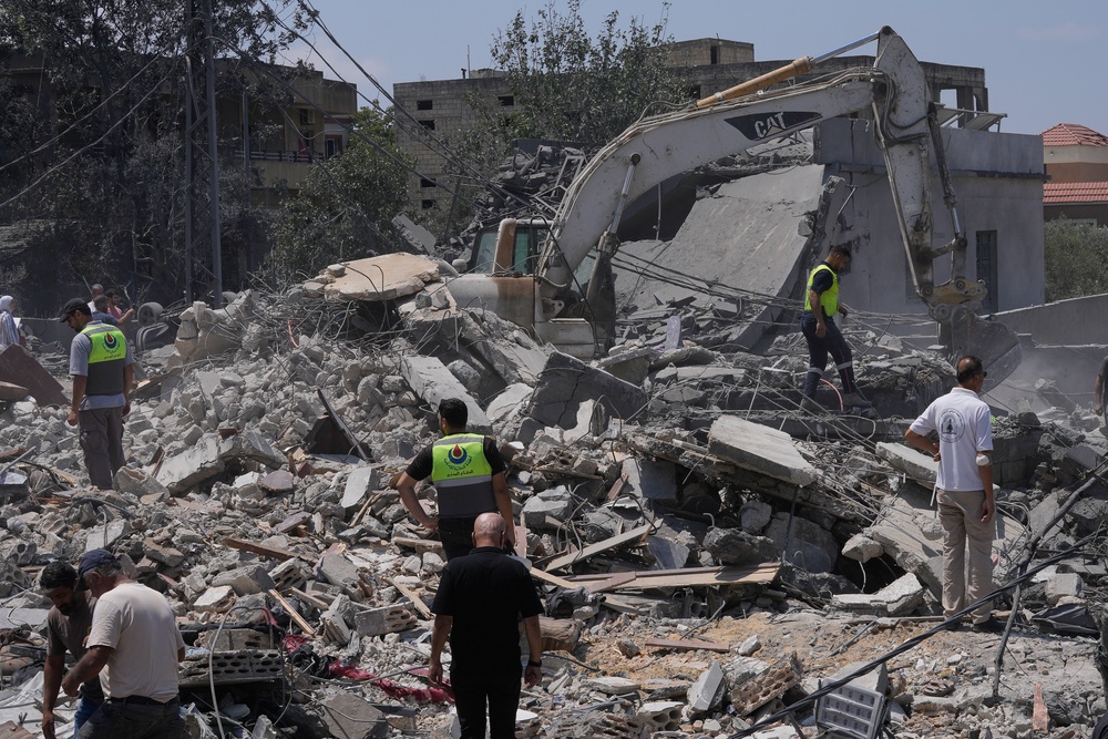 People and rescue workers gather on a destroyed house that was hit by an Israeli airstrike in southern Lebanon (AP)