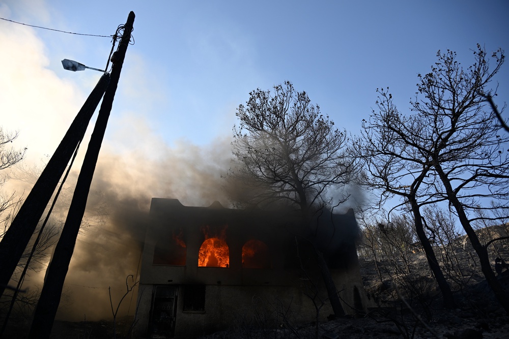 Flames burn in a house during a wildfire on the island of Salamina (AP)