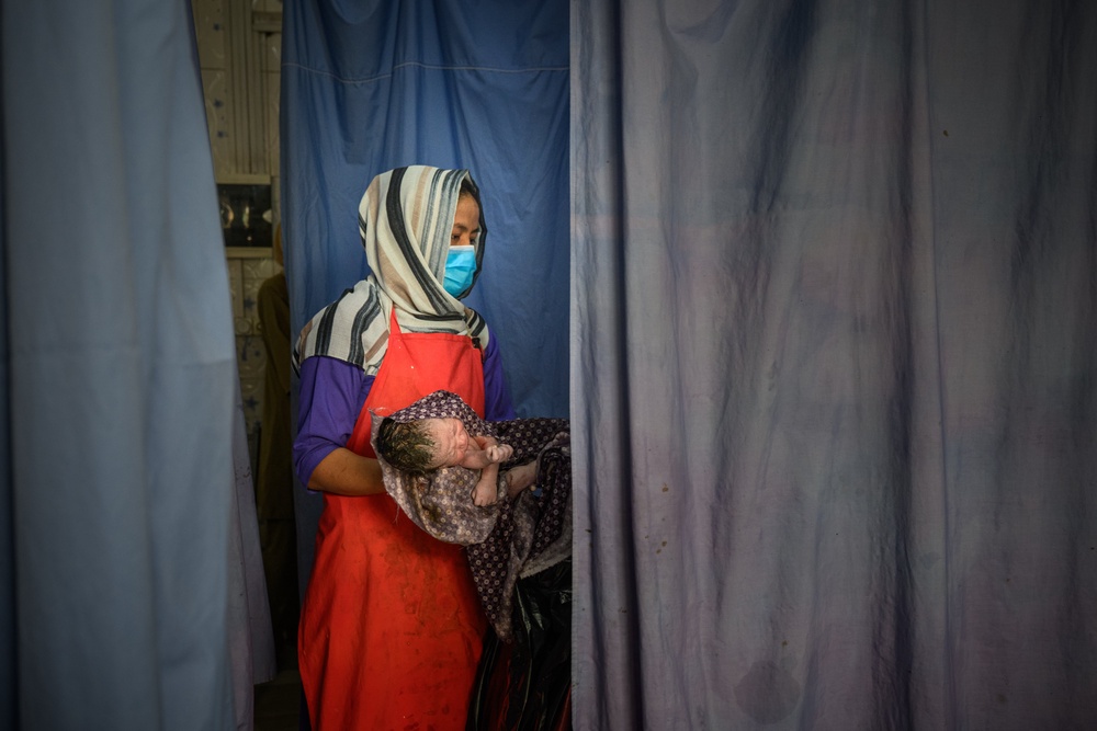 Midwife holds a newborn after a delivery at the provincial hospital's maternity unit in Ghazni (Getty)