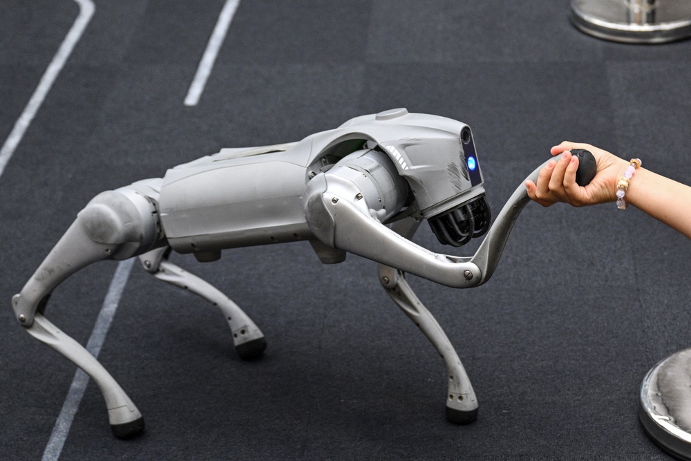 A girl holds the hand of a remote-controlled robot by Unitree Robotics while visiting the Unitree Robotics Embodied Intelligence Experience Center in the Jing' an district in Shanghai (AFP/Getty)