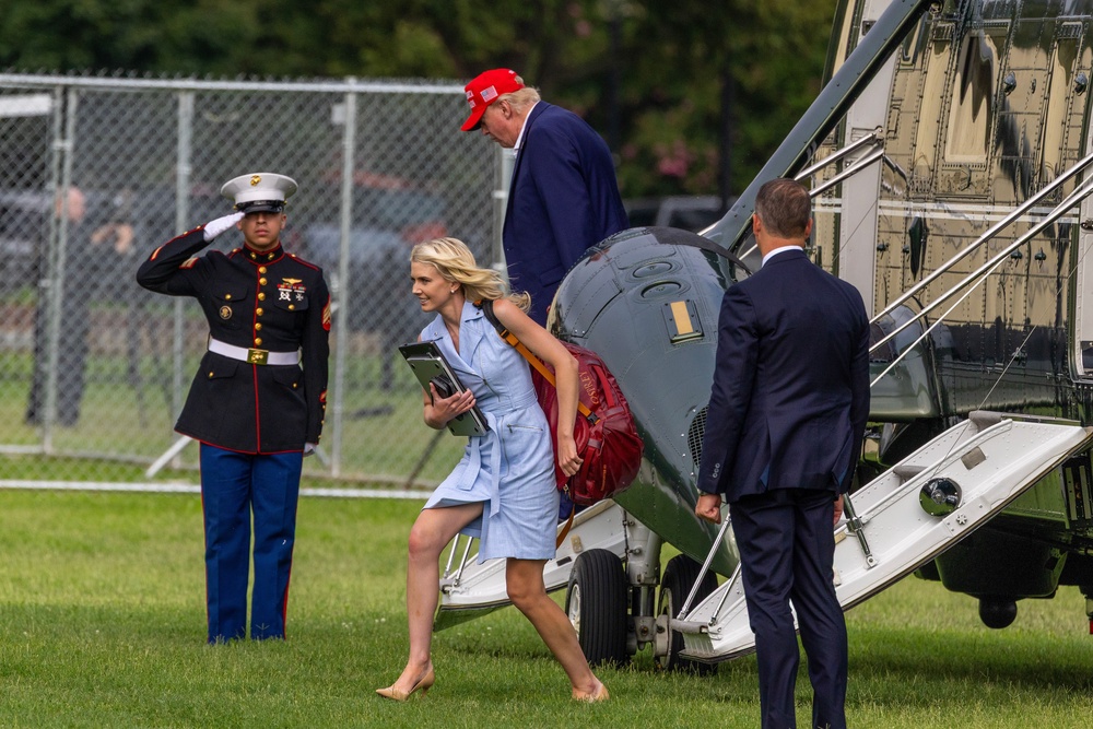 Harp (pictured center) closely follows the president, often with a stack of papers, to show Trump printed versions of social media posts, articles or messages (Getty)