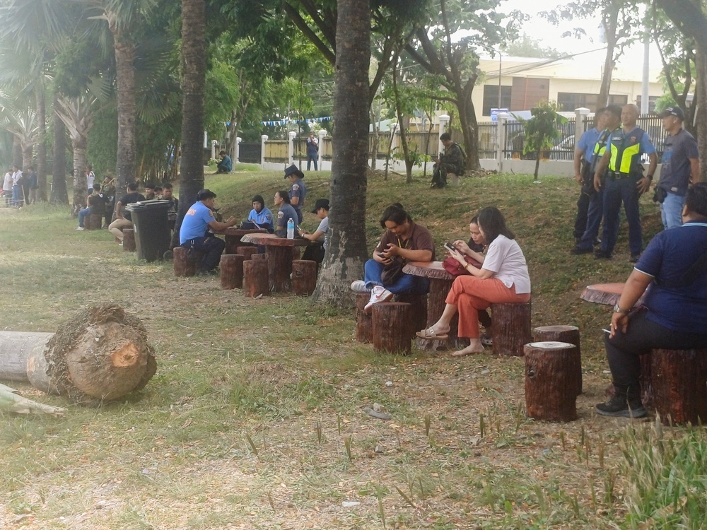 People sit outside Ateneo de Zamboanga University after a shooting that killed two people, in Zamboanga, southern Philippines, 18 August 2026 (Reuters)