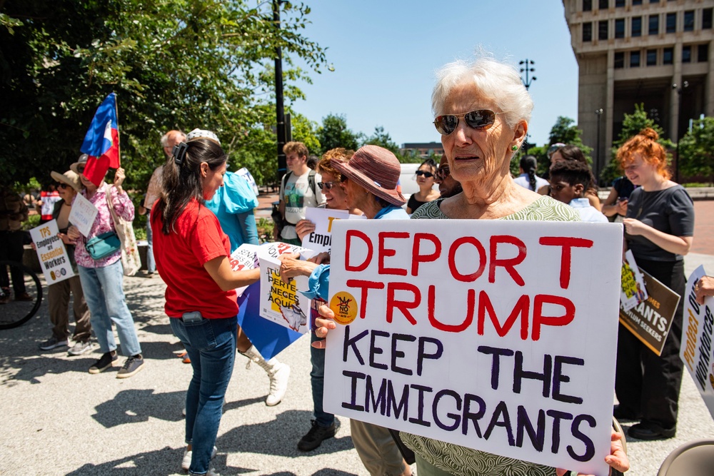 People hold signs at a rally calling on Congress to restore Temporary Protected Status (TPS) for Haitians, in Boston in July (Photo by JOSEPH PREZIOSO / AFP via Getty Images)