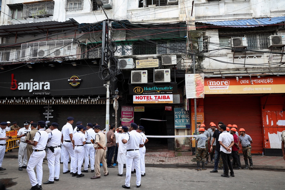 Firefighters and other officials stand on the street in the aftermath of a hotel fire that killed several people in Kolkata (Reuters)