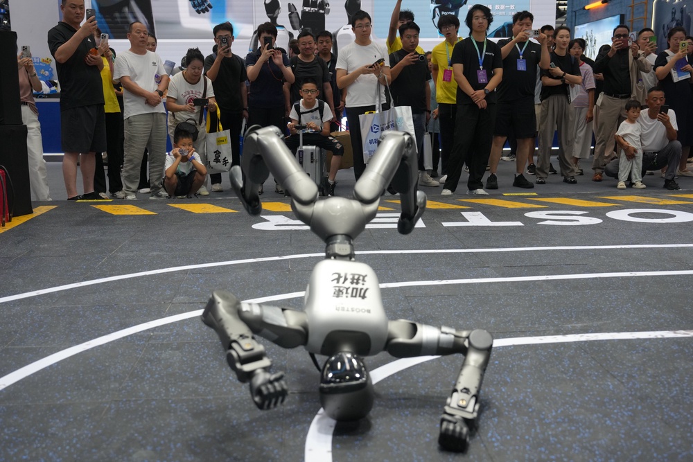 Visitors watch a humanoid robot at a booth (AP)