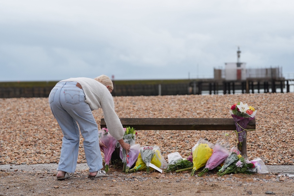 A person lays a floral tribute on the beach at Shoreham-by-Sea (Yui Mok/PA) (PA Wire)