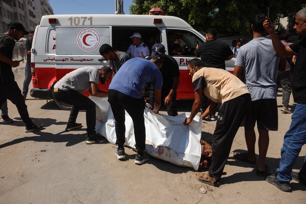 Displaced Palestinians carry the body of a victim away from the site of an Israeli strike in Gaza on Wednesday (AFP/Getty)