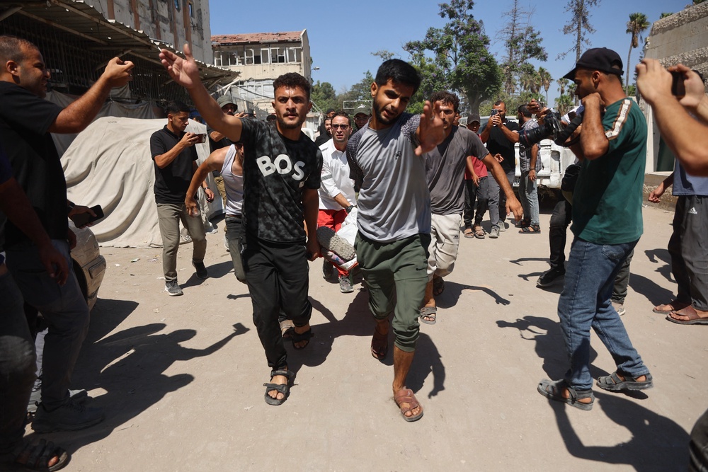 Palestinians carry the bodies of those killed and injured by Israeli strikes targeting the municipal police headquarters in Gaza City (AFP/Getty)