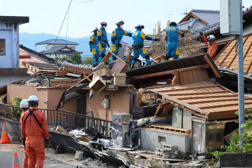 Rescue officials work at the site of a house damaged in an earthquake in Yatsushiro, Japan, last month. The East Asian country saw a 6.8-magnitude quake (JIJI Press/AFP via Getty Images)