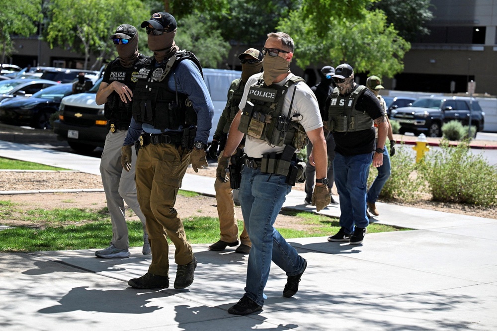 Masked law enforcement officers, including HSI and ICE agents, walk into an immigration court in Phoenix (Reuters)