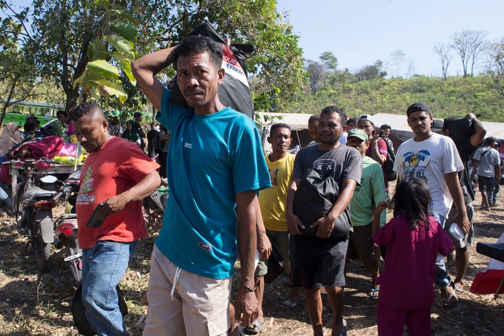 Earthquake survivors carry relief goods in North Lamba Leda, East Nusa Tenggara province, Indonesia (AP)