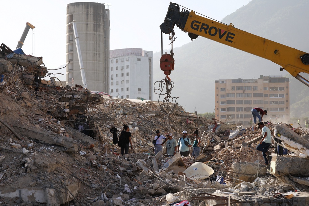 People work to remove debris from a collapsed building, as Venezuelans face worsening power and water shortages following government warnings of drought linked to the El Nino phenomenon (Reuters)