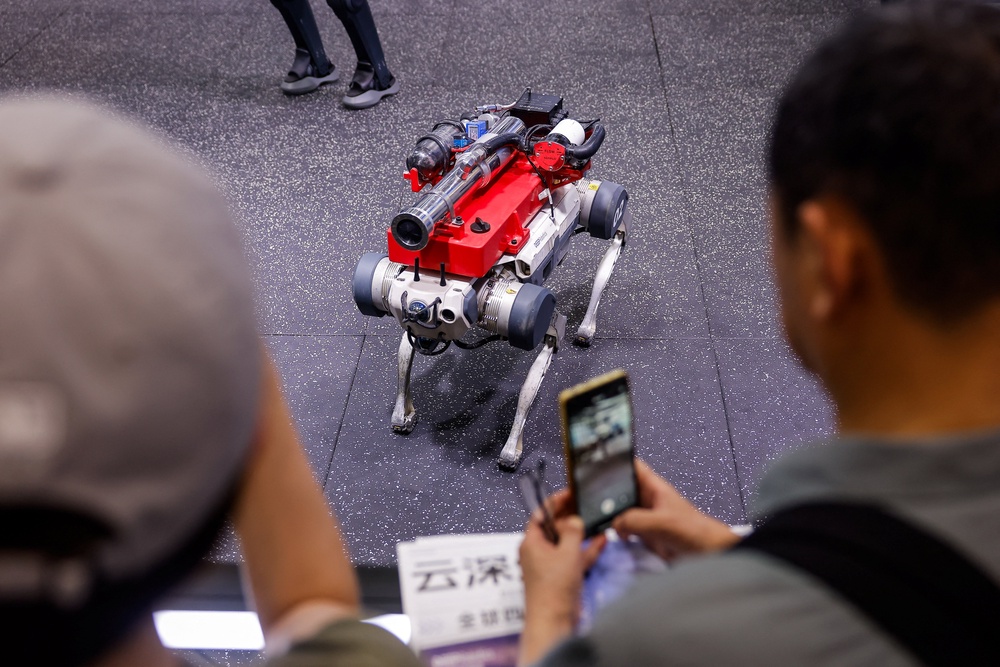 People take pictures of a Deep Robotics X30 robot dog at the company's booth at the 2026 World Robot Conference (Reuters)