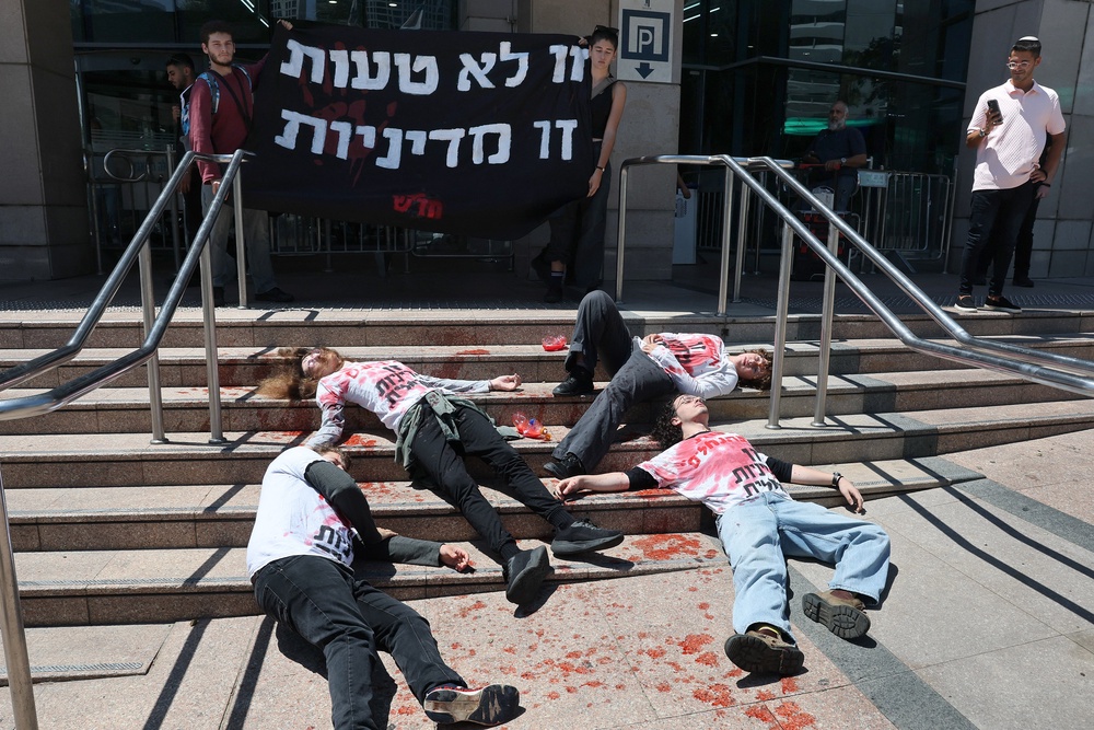 Activists in red-stained T-shirts take part in a die-in protest in the Israeli coastal city of Tel Aviv on August 19, 2026, against recent violent attacks by Israeli settlers in the Israeli-occupied West Bank (AFP/Getty)