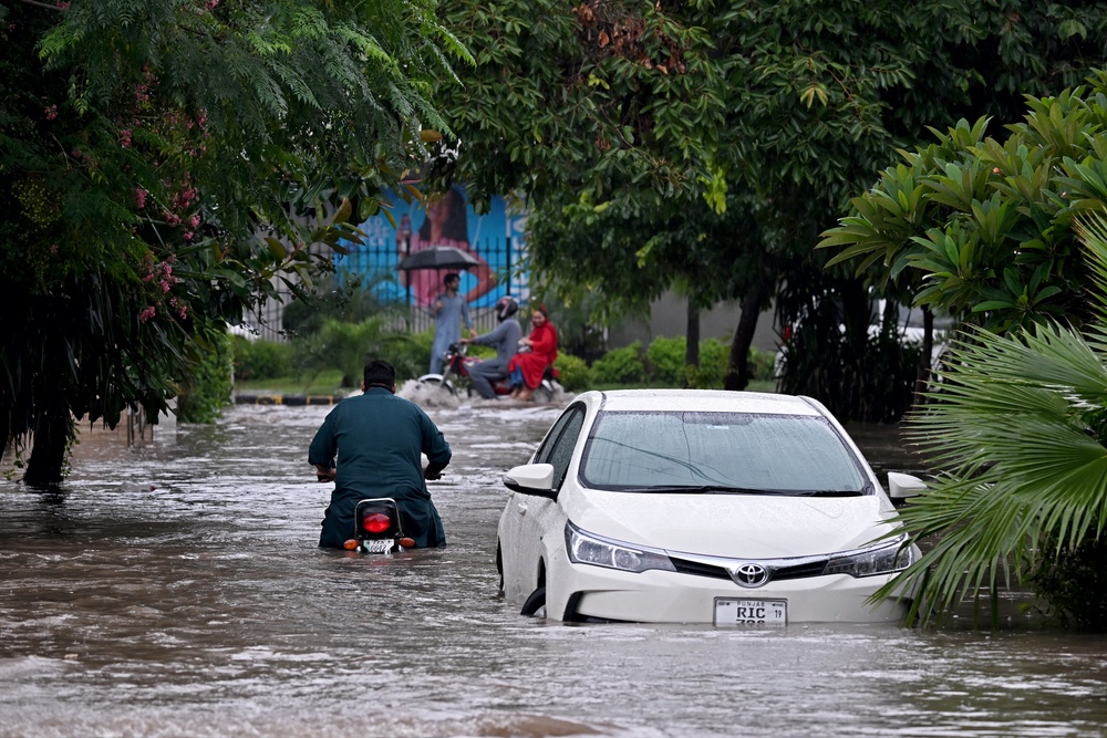 Commuters wade through a flooded street after heavy rainfall in Rawalpindi, Pakistan (AFP/Getty)