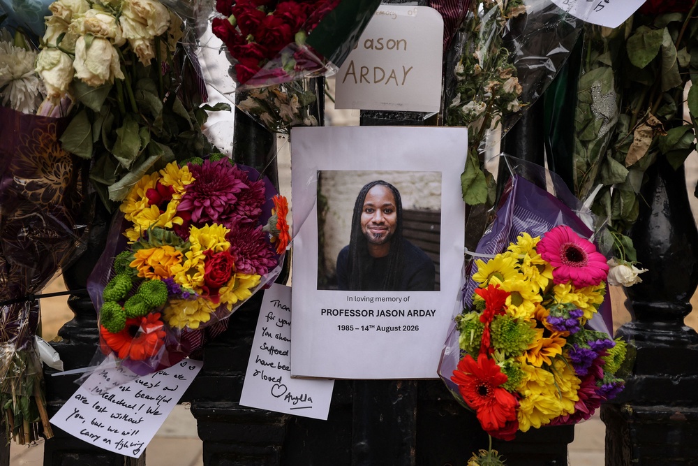 A photo of late Cambridge professor Jason Arday is pictured along with floral tributes, attached to the fencing by supporters around the Senate House at the University of Cambridge, in the town of Cambridge, eastern England on August 18, 2026 (AFP/Getty)